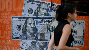 Una mujer camina junto a una imagen de billetes de cien d�lares estadounidenses en Buenos Aires.